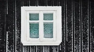 Lite hvitt vindu med fire ruter på mørk trekledning med spor av snø