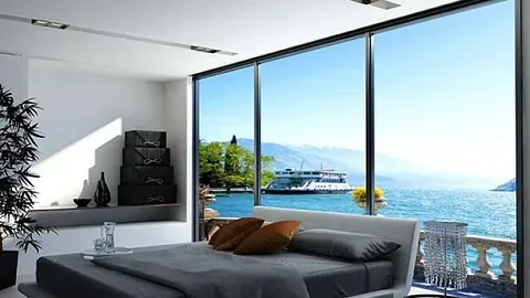 Soverom med panoramavinduer og utsikt mot sjø, fjell og en båt ved kai